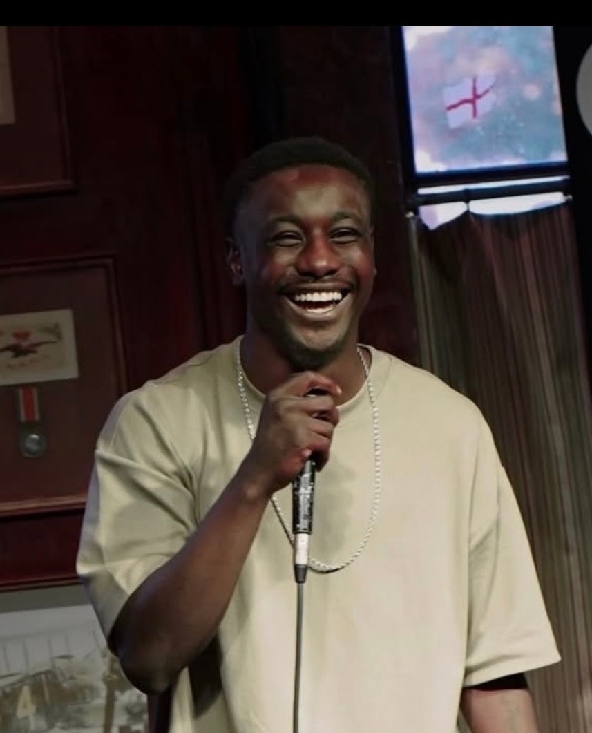 Comedian laughing and holding microphone on stage